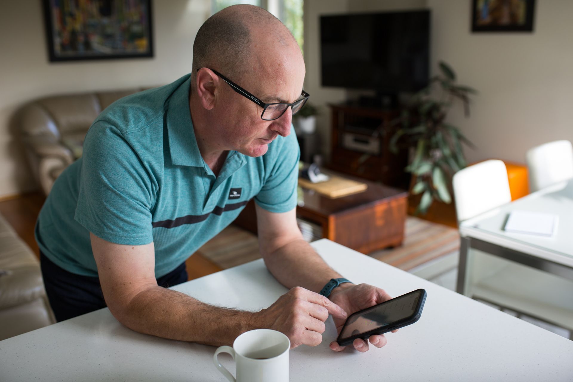 A man is sitting at a table looking at a cell phone.