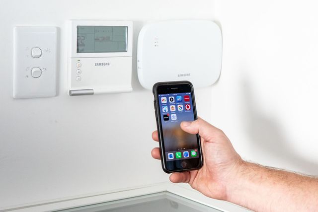 A person holding a phone in front of a solar inverter